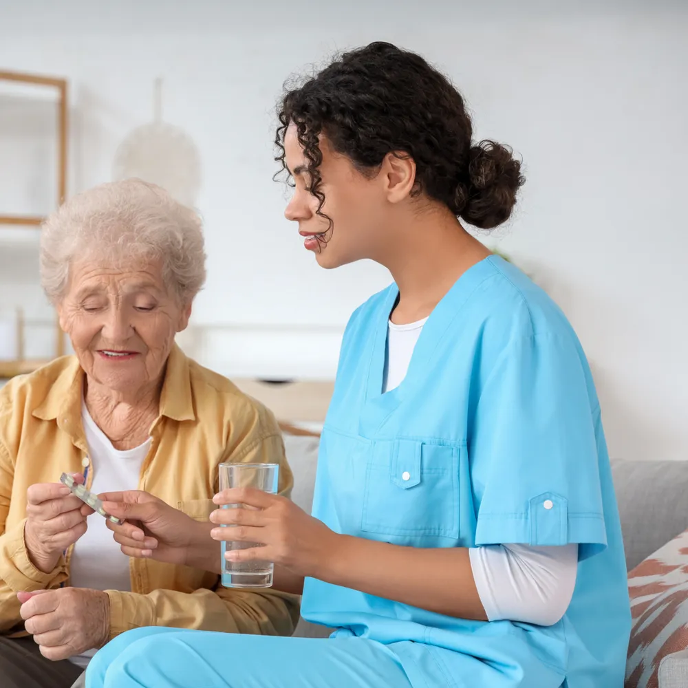 Care worker in scrubs helping an elderly resident with medication