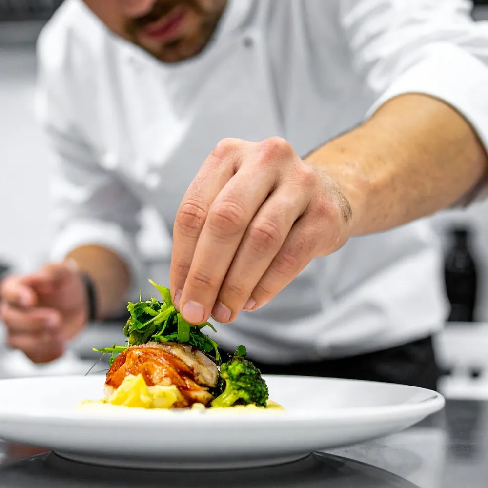 Chef in whites plating a dish
