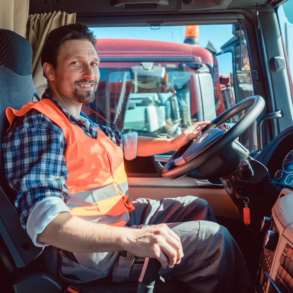 Lorry driver in a hi-vis vest sitting in the cab of an HGV