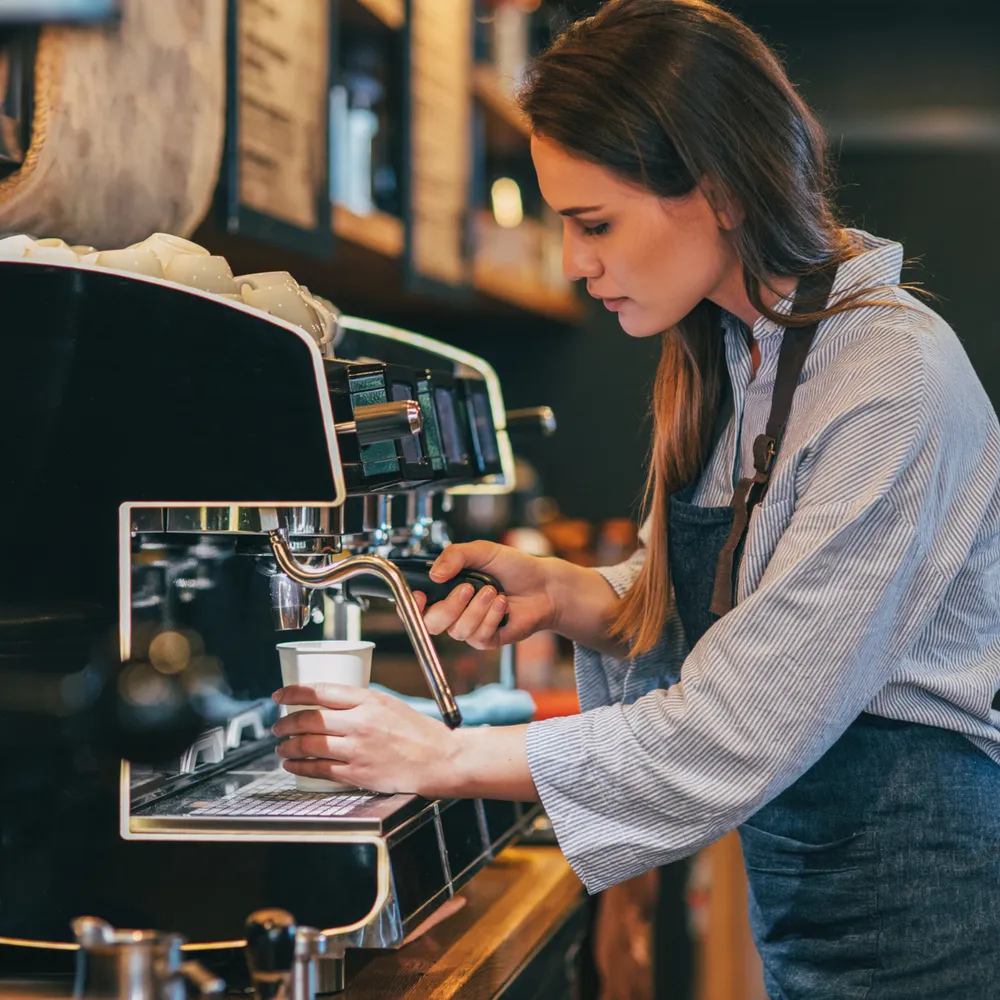 Barista in an apron preparing coffee at an espresso machine
