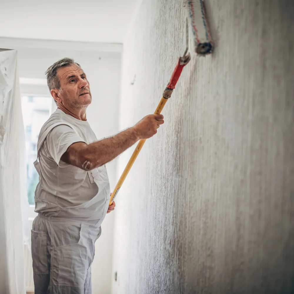 Painter in whites rolling a wall