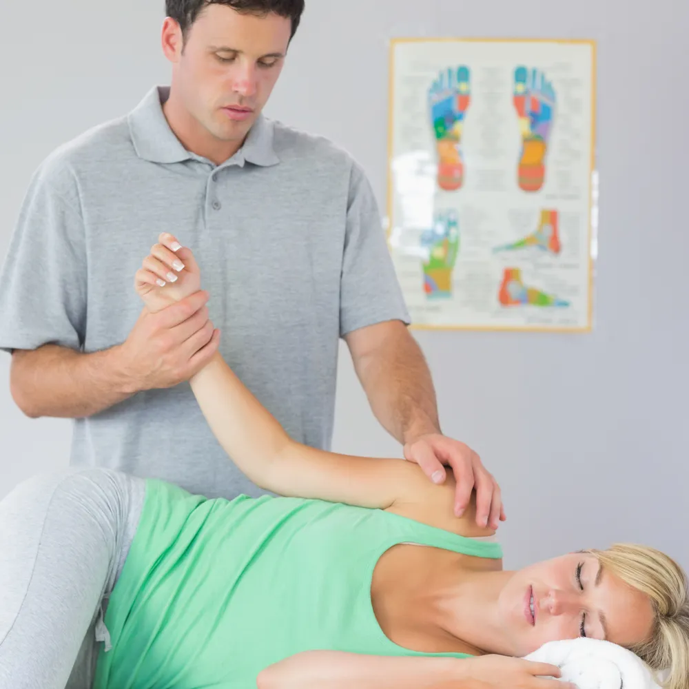 Physiotherapist in a polo shirt treating a patient in a clinic