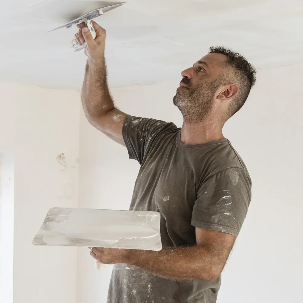 Plasterer skimming a ceiling with a trowel and hawk