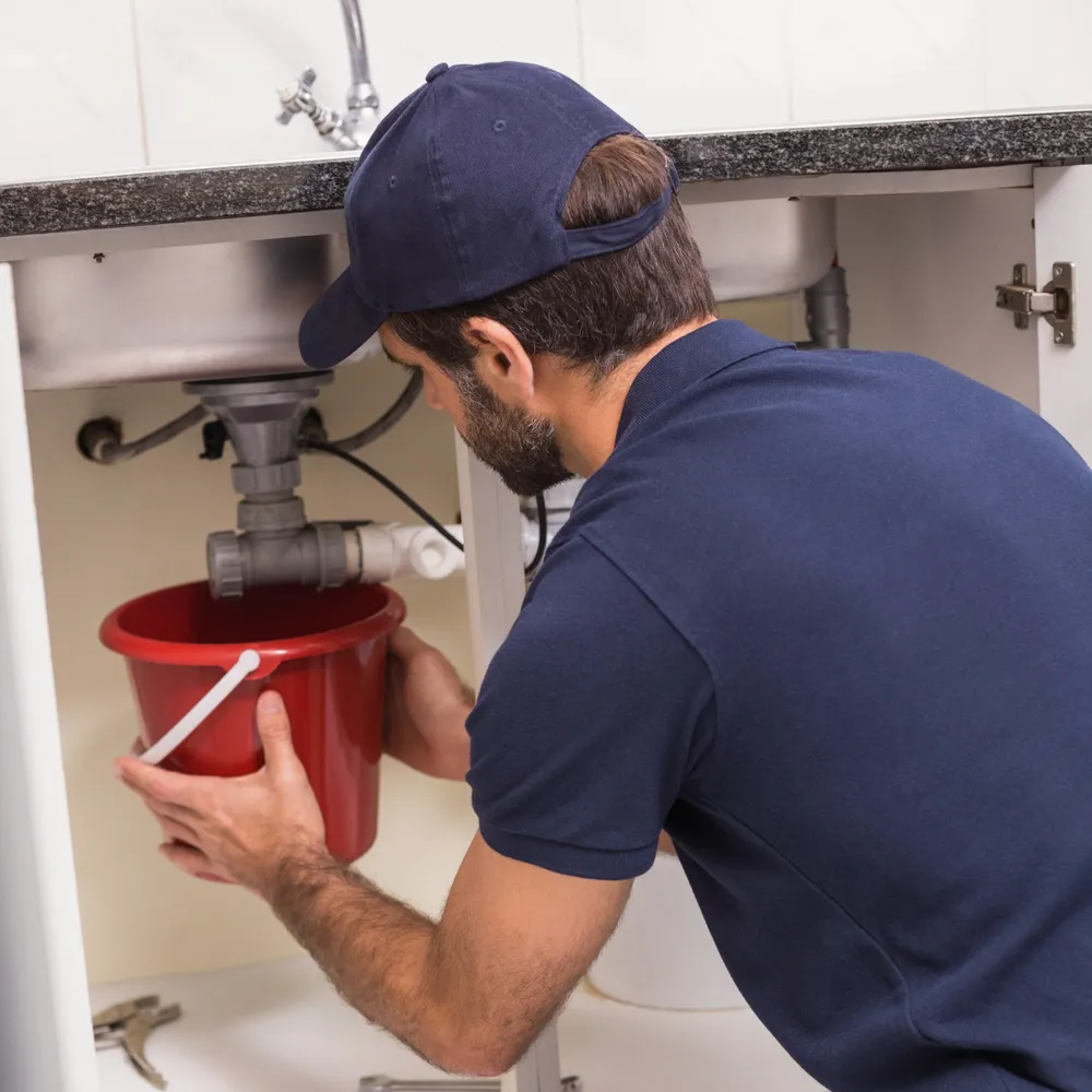 Plumber working on the waste trap under a kitchen sink