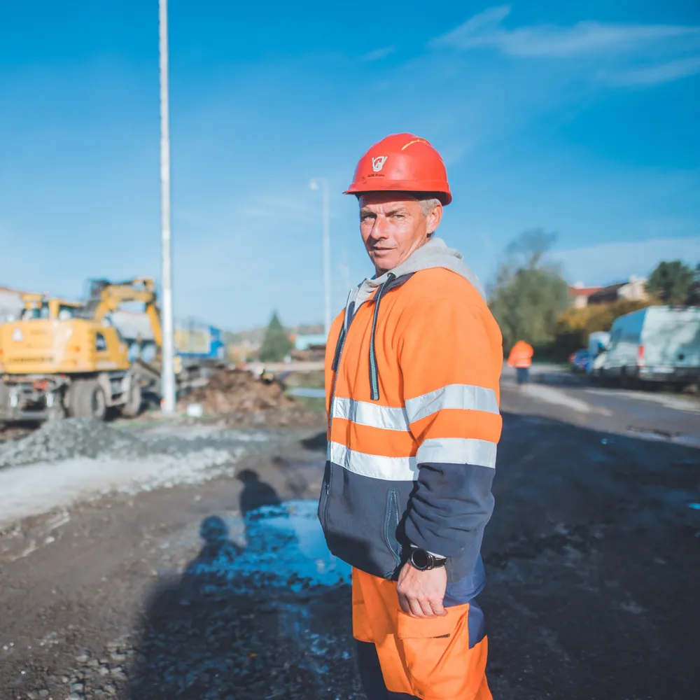 Worker in full orange hi-vis clothing and safety helmet on an infrastructure site
