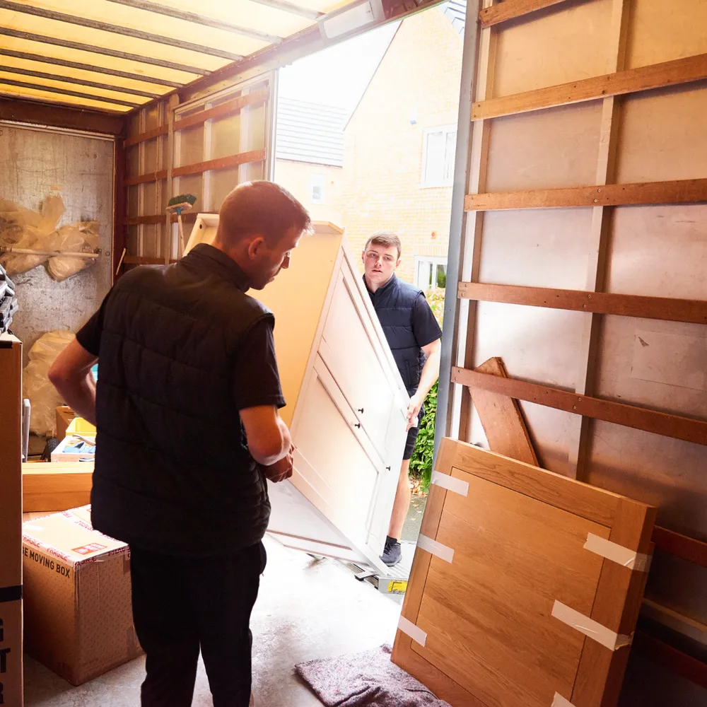 Two removals workers loading furniture into a removal van