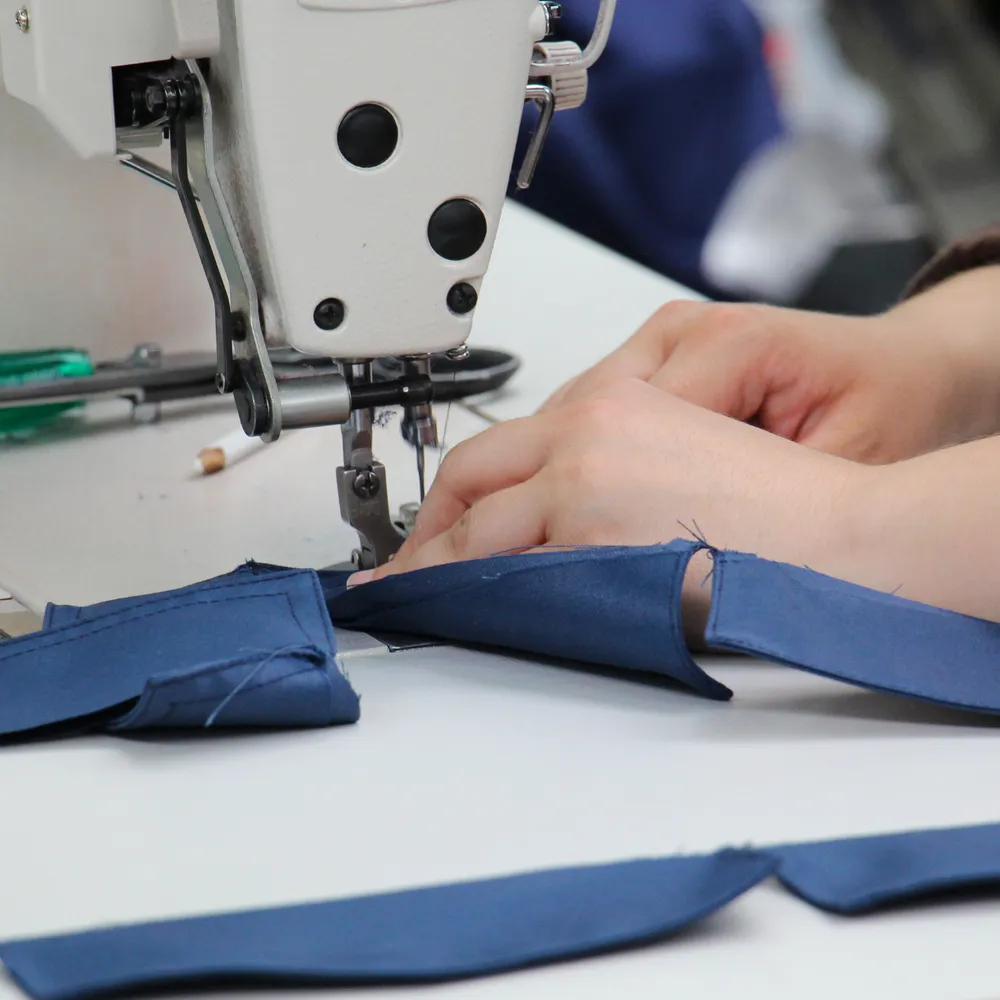 Machinist sewing navy fabric on an industrial machine