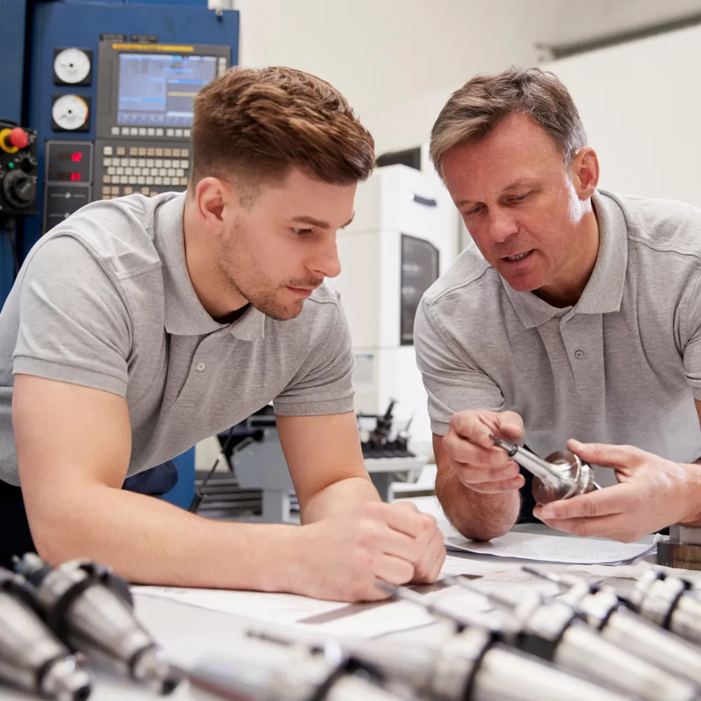 Engineers checking precision tooling at a CNC machine