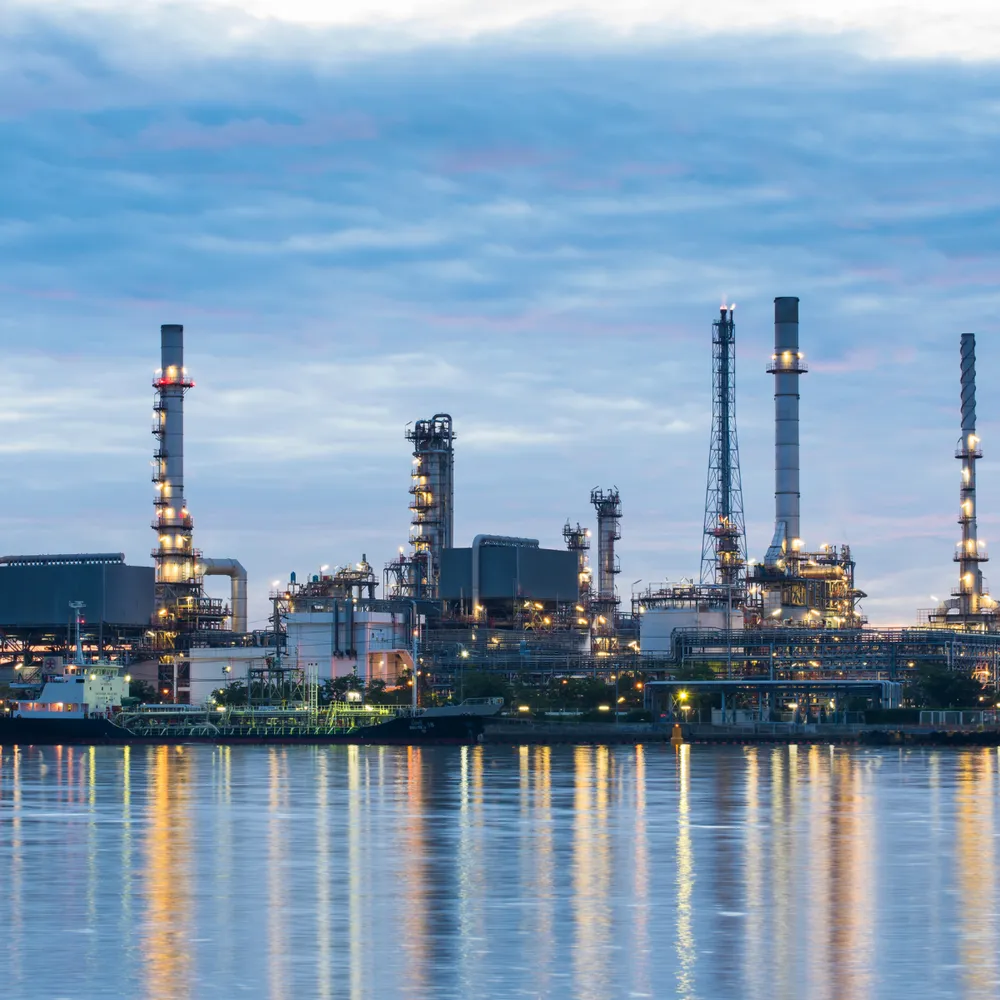 Refinery complex lit at dusk across the water