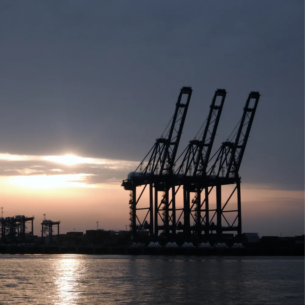 Container cranes silhouetted at sunset