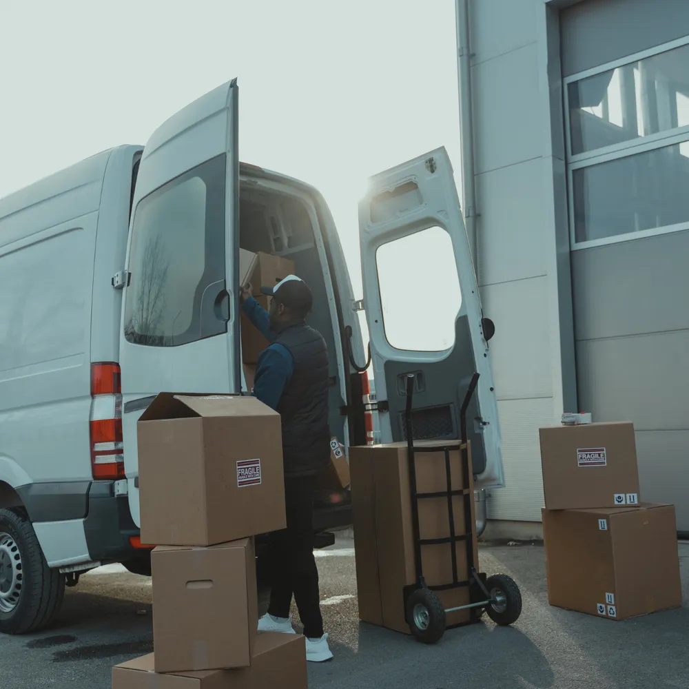 Courier loading boxes into a van at a depot