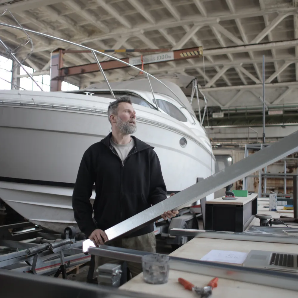 Boatbuilder working beside a motor cruiser in a boatyard shed