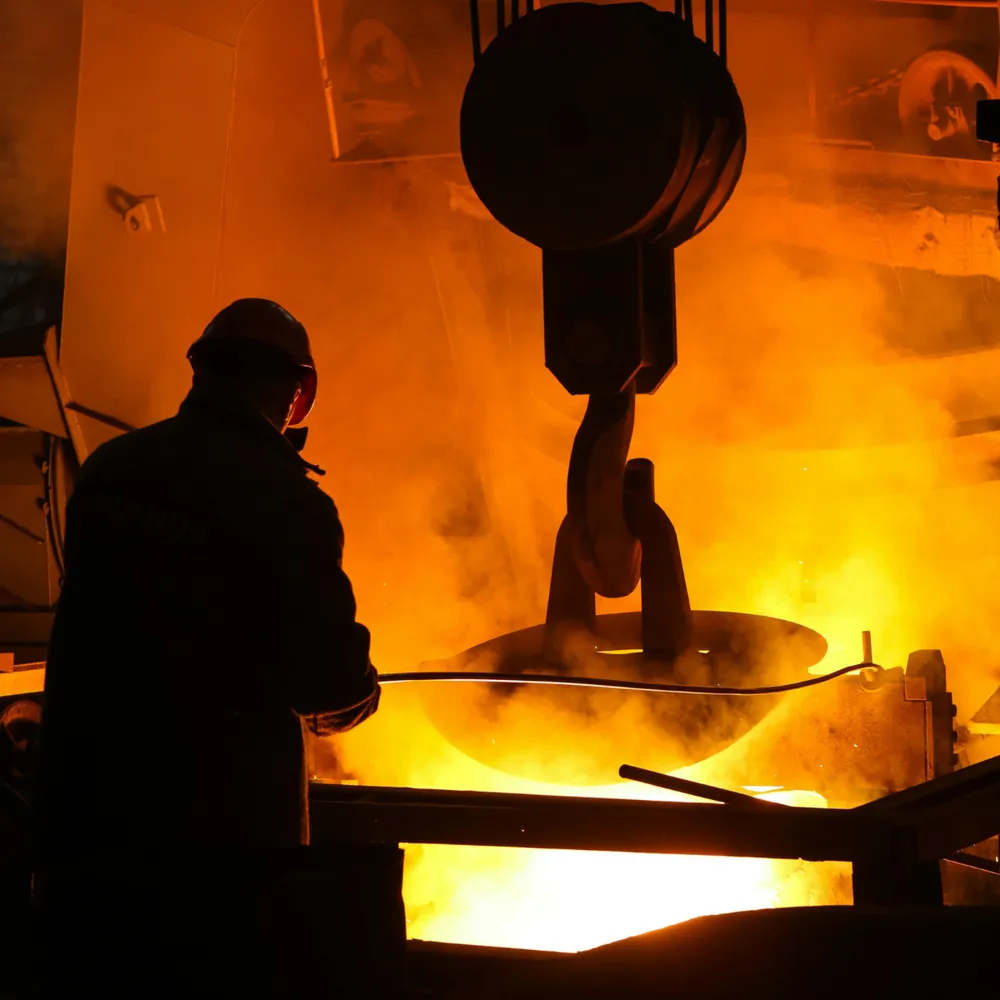 Foundry worker beside a ladle of molten metal
