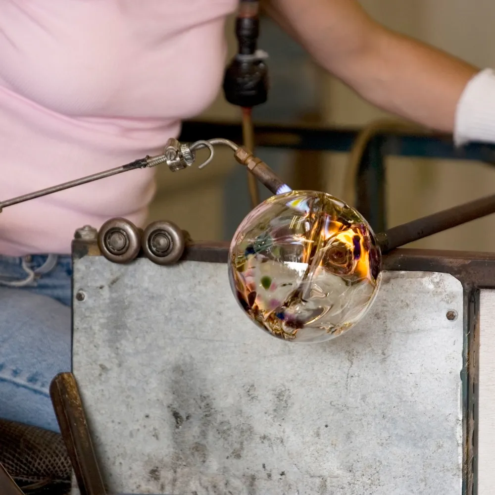 Glassworker shaping molten glass with a torch