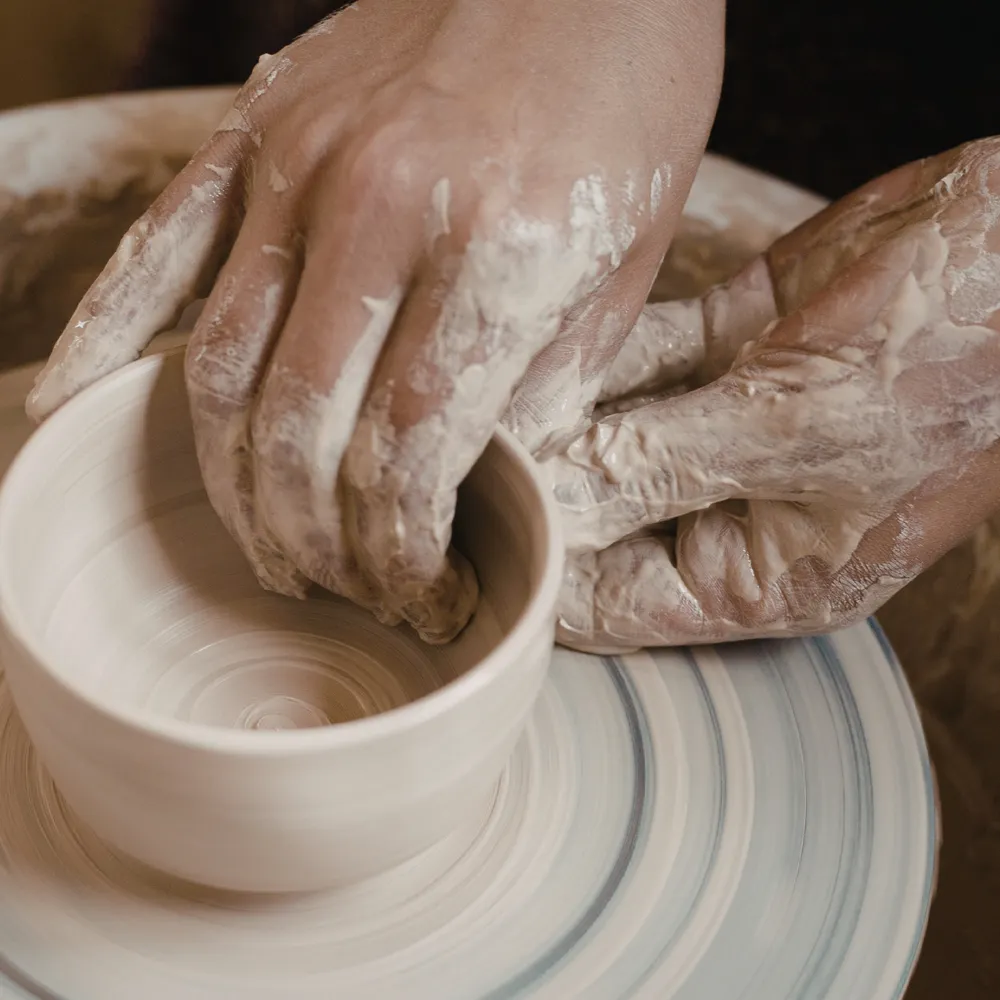 Potter's hands shaping a bowl on the wheel
